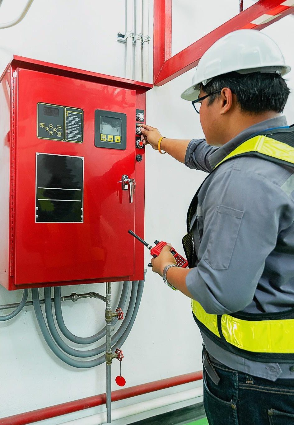 Fire protection technician inspecting a commercial fire alarm control panel in a San Diego facility.