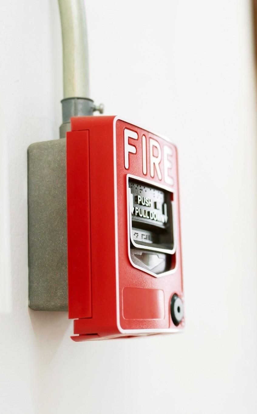 Commercial fire alarm pull station with fire extinguisher in the background