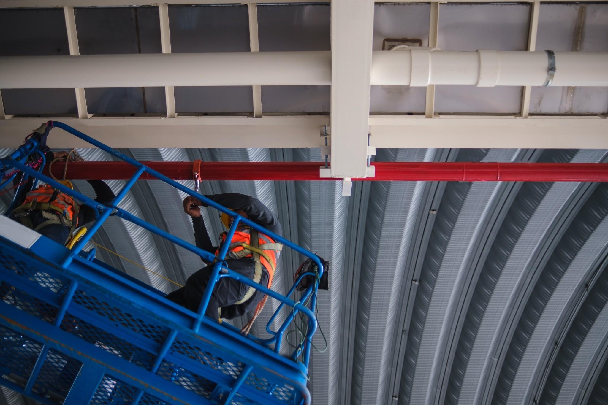 Technician installing commercial fire sprinkler piping from an aerial lift